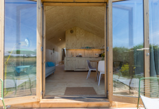 Entrada a un Wikkelhouse en Welcome In - Zeeland, Países Bajos, con interior moderno y vistas al exterior.