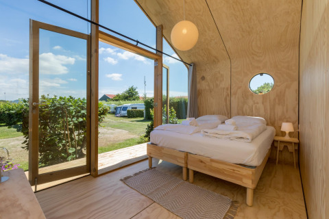 Interior de una Wikkelhouse en Welcome In - Zeeland, Países Bajos, con diseño de madera y vista al jardín.