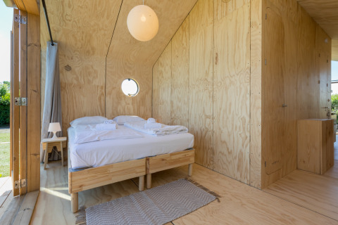 Schlafzimmer mit Holzwänden und Doppelbett in einem Wikkelhouse bei Welcome In - Zeeland, Niederlande.