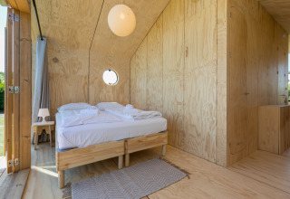 Schlafzimmer mit Holzwänden und Doppelbett in einem Wikkelhouse bei Welcome In - Zeeland, Niederlande.
