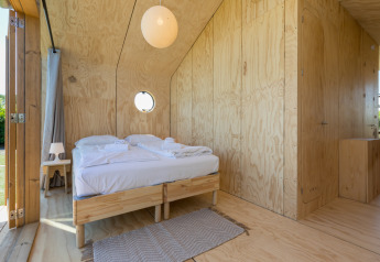 Slaapkamer met houten wanden en tweepersoonsbed in een Wikkelhouse bij Welcome In - Zeeland, Nederland.