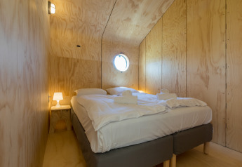 Gemütliches Schlafzimmer in einem Wikkelhouse bei Welcome In - Zeeland, Niederlande, mit Holzverkleidung.
