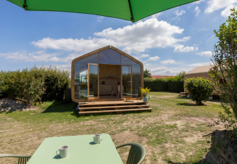 Uitzicht op een Wikkelhouse bij Welcome In - Zeeland, Nederland, met terras, tafel, stoelen en groene parasol.