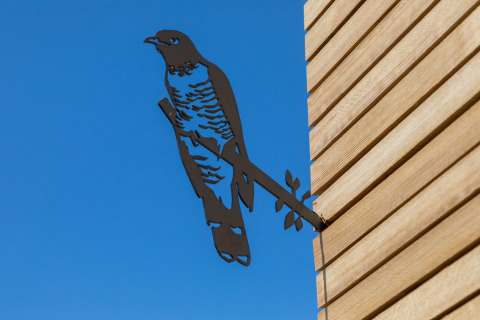 Escultura de pájaro de metal en la pared exterior de un Wikkelhouse en Welcome In - Zeeland, Países Bajos.