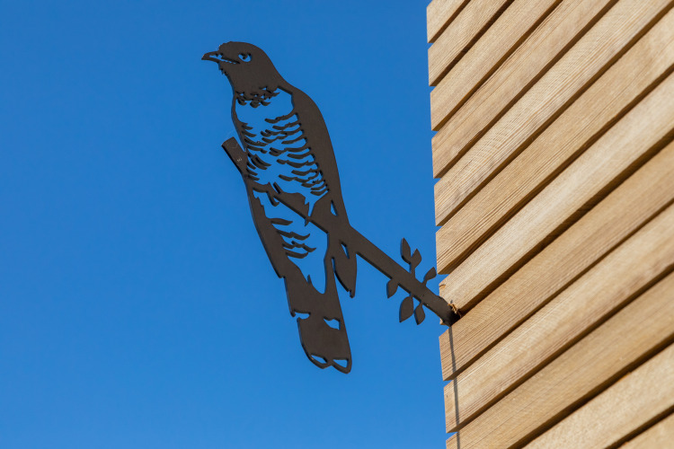 Escultura de pájaro de metal en la pared exterior de un Wikkelhouse en Welcome In - Zeeland, Países Bajos.
