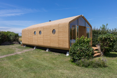 Wikkelhouse en Welcome In - Zeeland, Países Bajos, casa moderna y sostenible de madera rodeada de césped.