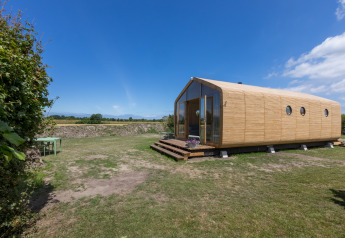Moderna Wikkelhouse a Welcome In - Zeeland, Paesi Bassi, con esterno in legno e ampio prato verde.
