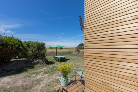 Uitzicht op tuin met groene parasol en modern houten Wikkelhouse bij Welcome In - Zeeland, Nederland.