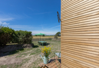 Vista sul giardino con ombrellone verde e moderno Wikkelhouse in legno a Welcome In - Zeeland, Paesi Bassi.