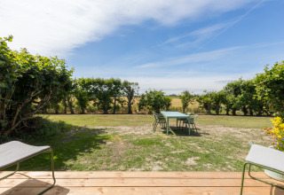 Uitzicht vanaf een terras op een tuin met tafel en stoelen in Wikkelhouse, Welcome In - Zeeland, Nederland.