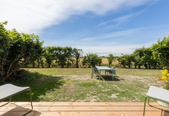 Uitzicht vanaf een terras op een tuin met tafel en stoelen in Wikkelhouse, Welcome In - Zeeland, Nederland.