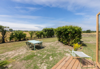 Spazio esterno di una Wikkelhouse con tavolo e sedie, prato e vista su campi a Zeeland, Paesi Bassi.