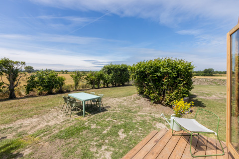Außenbereich eines Wikkelhouse bei Welcome In - Zeeland, mit Tisch, Stühlen und Blick auf Felder.