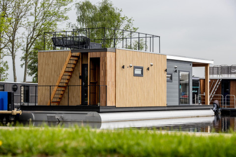 Moderna casa flotante con revestimiento de madera y terraza en el techo en Friesland, Países Bajos.