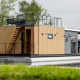 Moderne Hausboot mit Holzverkleidung und Dachterrasse, vertäut am Wasser in Friesland, Niederlande.