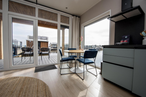 Comedor moderno en un lodge flotante con grandes ventanas y vistas al agua en Friesland, Países Bajos.