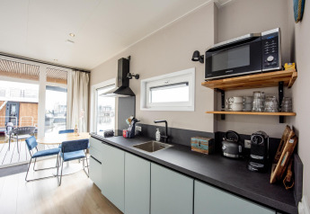Cucina moderna e zona pranzo su Houseboat 'Riggelbrug' a Welcome In - Friesland, Olanda, con microonde.