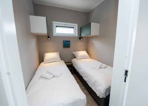 Habitación luminosa con dos camas individuales en la Houseboat 'Riggelbrug' en Welcome In - Friesland, Países Bajos.