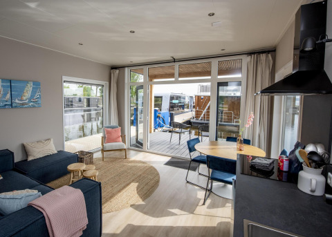 Wohnzimmer und Küche im Hausboot 'Riggelbrug' mit Terrasse und Wasserblick bei Welcome In - Friesland.