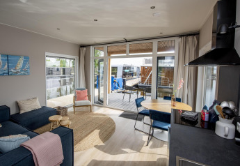 Living room and kitchen of Houseboat 'Riggelbrug' at Welcome In - Friesland, Netherlands, with water view.