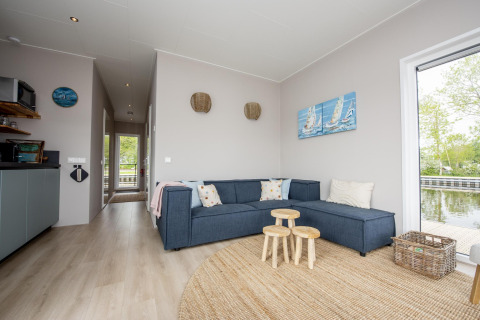Sala de estar moderna en Houseboat 'Riggelbrug' en Friesland, Países Bajos, con vista al agua.