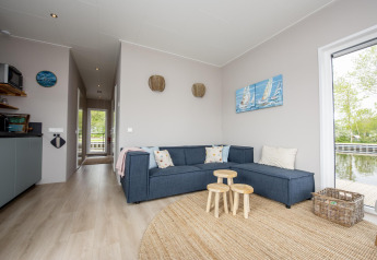 Modern living area at Houseboat 'Riggelbrug' in Friesland, Netherlands, with large windows facing the water.