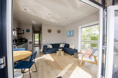 Vista interior de la Houseboat 'Riggelbrug' con espacio moderno y vista al agua en Friesland, Países Bajos.