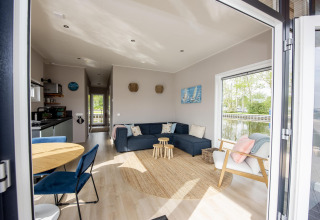 Vista interior de la Houseboat 'Riggelbrug' con espacio moderno y vista al agua en Friesland, Países Bajos.