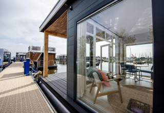 Moderne Hausboot in Friesland, Niederlande, mit großen Fenstern und Blick auf den Jachthafen.