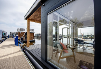 Moderne Hausboot in Friesland, Niederlande, mit großen Fenstern und Blick auf den Jachthafen.