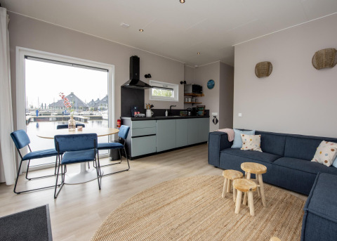 Modernes Wohnzimmer im Hausboot 'Riggelbrug' mit offener Küche und Wasserblick in Friesland, Niederlande.