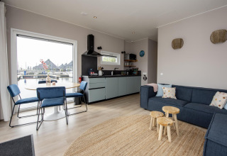 Modernes Wohnzimmer im Hausboot 'Riggelbrug' mit offener Küche und Wasserblick in Friesland, Niederlande.