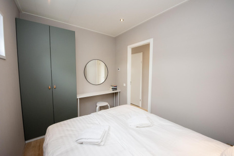 Dormitorio en Houseboat 'Riggelbrug' con cama doble, armario y escritorio en Friesland, Países Bajos.