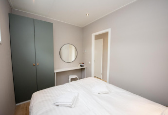 Bedroom at Houseboat 'Riggelbrug' with double bed, wardrobe, desk and chair at Friesland, Netherlands.