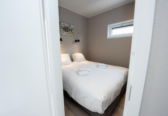 Camera da letto moderna con letto matrimoniale, lenzuola bianche e asciugamani in Houseboat 'Riggelbrug', Frisia.