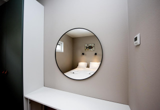 Moderne kamer op Houseboat 'Riggelbrug', Friesland, met ronde spiegel die het bed reflecteert.