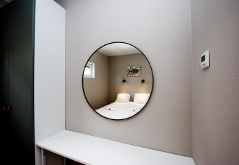 Camera moderna nella Houseboat 'Riggelbrug', Friesland, con specchio tondo che riflette un letto matrimoniale.