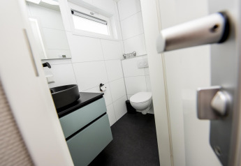 Bagno moderno con wc sospeso, lavabo nero e finestra sulla Houseboat 'Riggelbrug' a Friesland, Paesi Bassi.