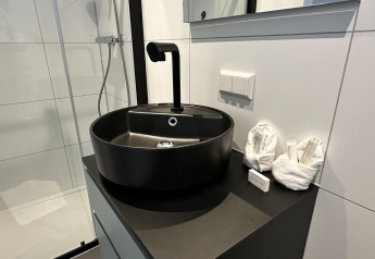 Bagno moderno con lavabo rotondo nero, rubinetto elegante e asciugamani piegati sul piano d'appoggio nero.