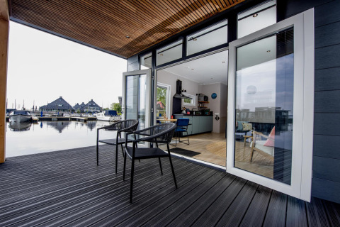Casa flotante moderna con terraza abierta y vistas al puerto deportivo en Welcome In - Friesland, Países Bajos.