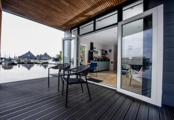 Modern houseboat lodge with open terrace overlooking marina at Welcome In - Friesland, Netherlands.
