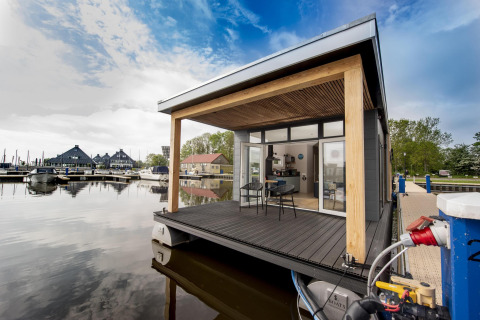 Moderno houseboat 'Riggelbrug' en Welcome In - Friesland, Países Bajos, flotando junto al puerto deportivo.
