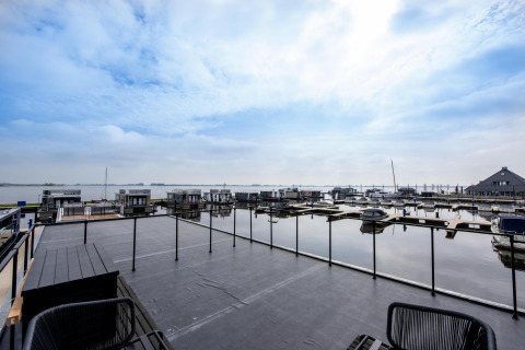 Vista desde la casa flotante 'Riggelbrug' en Welcome In - Friesland, Países Bajos, con muelle y embarcaciones.
