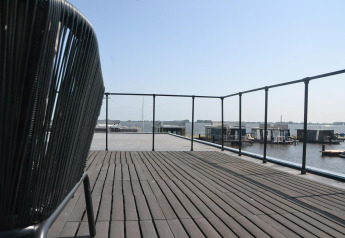 Ampia terrazza con vista sull'acqua e case galleggianti a Houseboat 'Riggelbrug' in Friesland, Paesi Bassi.