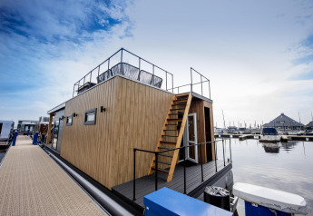 Moderna houseboat 'Riggelbrug' al Welcome In - Friesland nei Paesi Bassi, ormeggiata in un porto tranquillo.