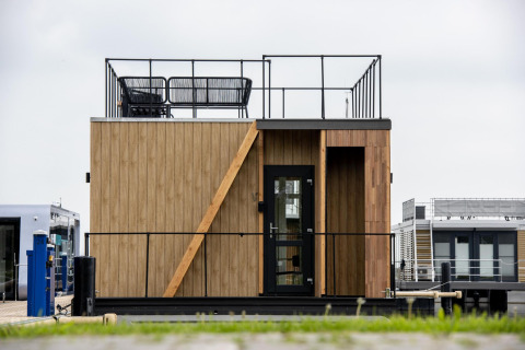 Casa flotante moderna con terraza y revestimiento de madera en Welcome In - Friesland, Países Bajos.