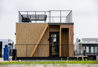 Casa flotante moderna con terraza y revestimiento de madera en Welcome In - Friesland, Países Bajos.