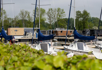 Barche e houseboat ormeggiate al lodge Houseboat 'Riggelbrug' a Welcome In - Friesland, Paesi Bassi, con verde.
