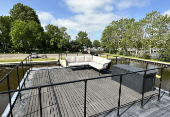 Terraza en la azotea de la casa flotante 'Riggelbrug' en Friesland, Países Bajos, con sofá y vistas.