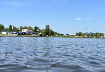 Blick über das Wasser auf das Hausboot 'Riggelbrug' bei Welcome In - Friesland, Niederlande, mit Booten.